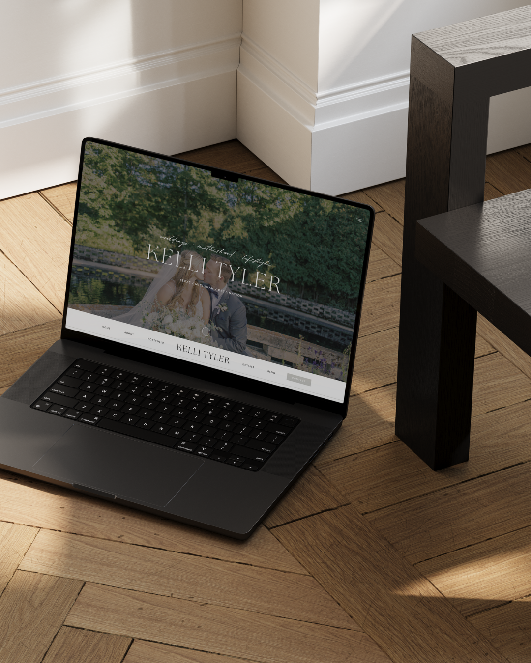 A black laptop on a wooden floor displays a Showit website design for photographers, featuring a couple embracing outdoors and the name “Kelli Tyler” prominently shown on the screen.