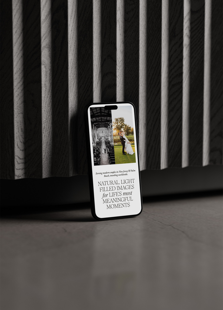 A smartphone leaning against a dark ribbed surface displays a photography website featuring a black-and-white photo of a wedding and the text, Natural, light-filled images for lifes most meaningful moments.